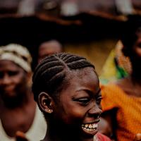 An African girl claps her hands and smiles.